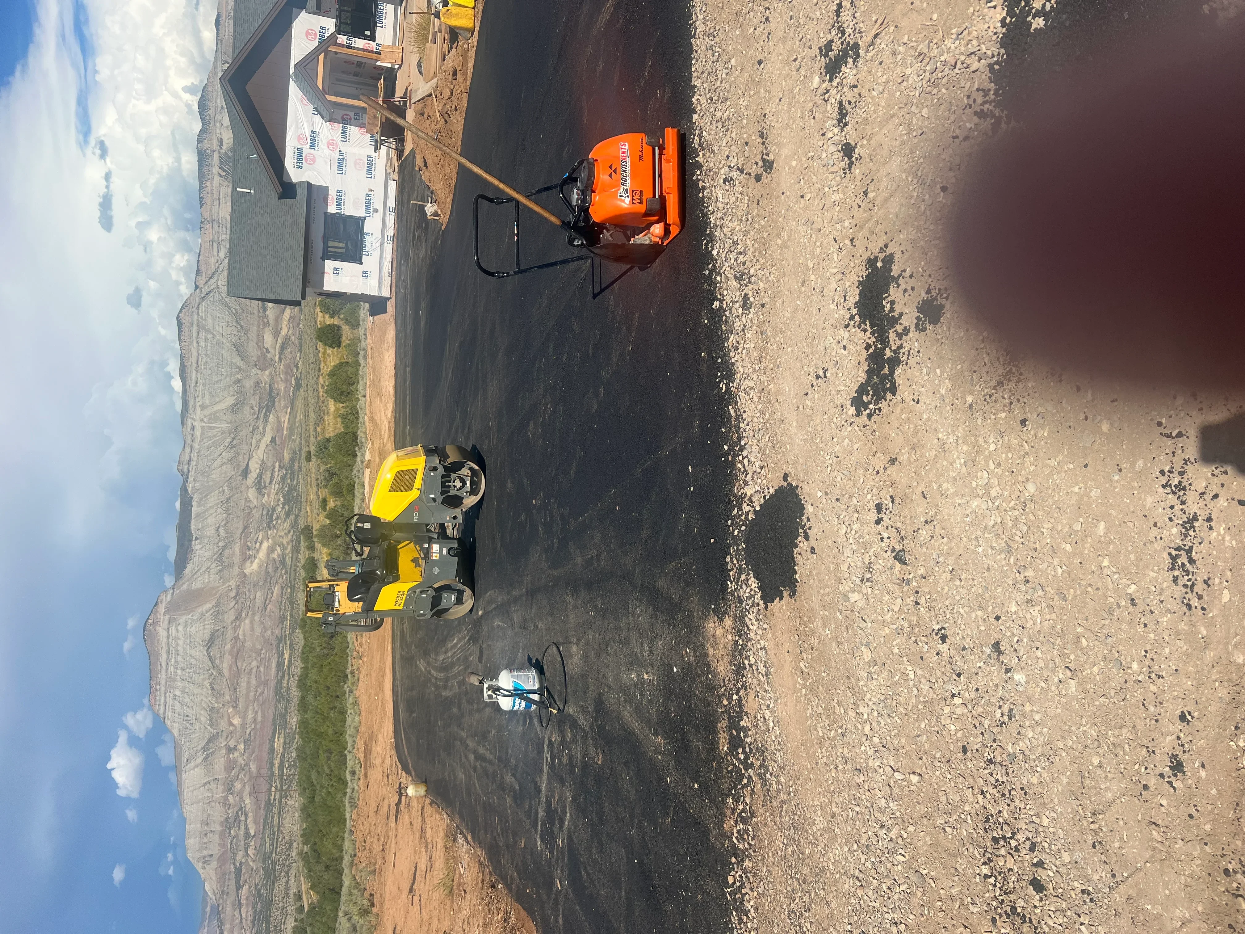 Asphalt paving equipment including vibratory roller and compactor on fresh asphalt surface