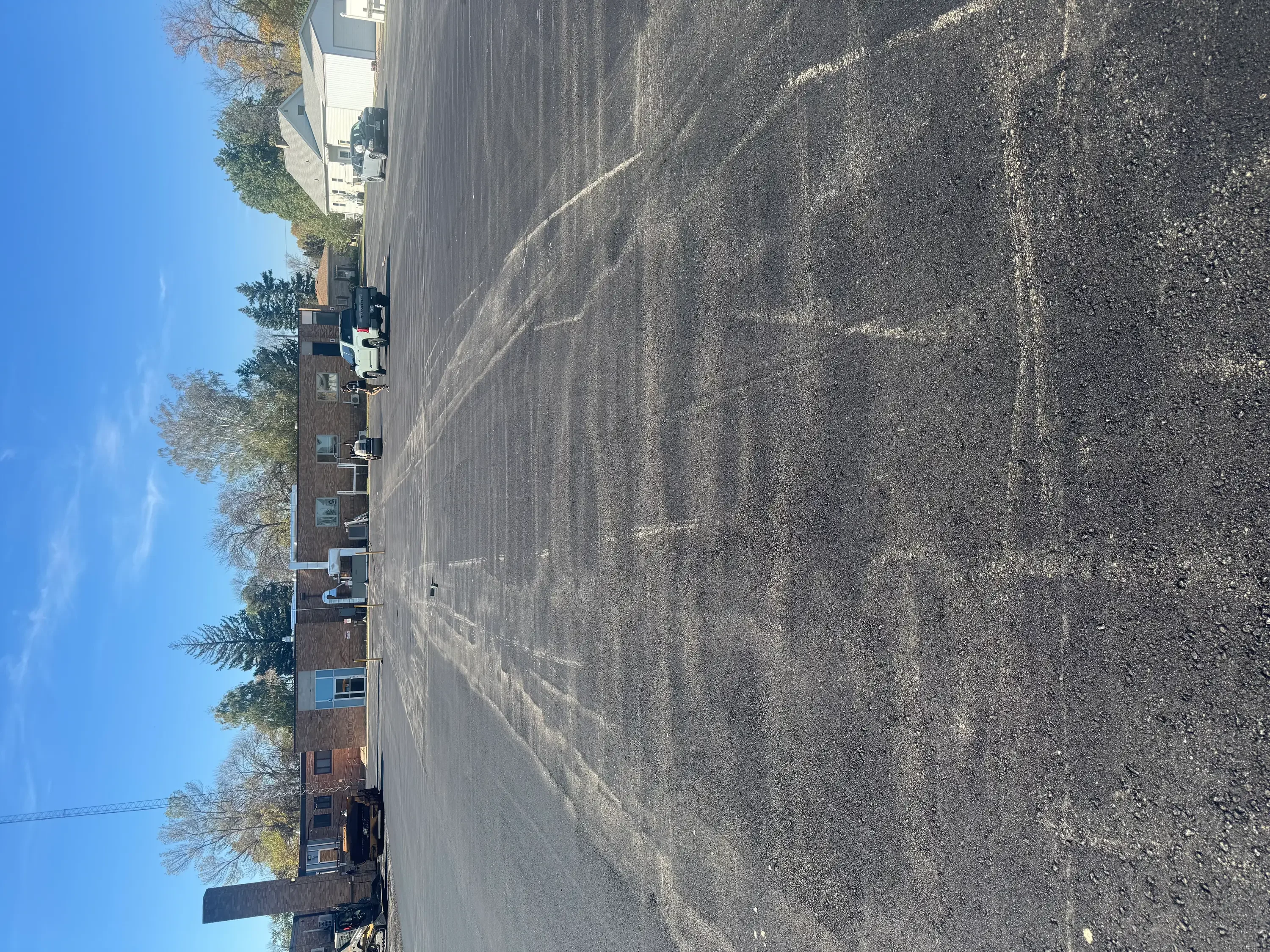 Newly paved asphalt driveway alongside brick residential home with clear surface finish