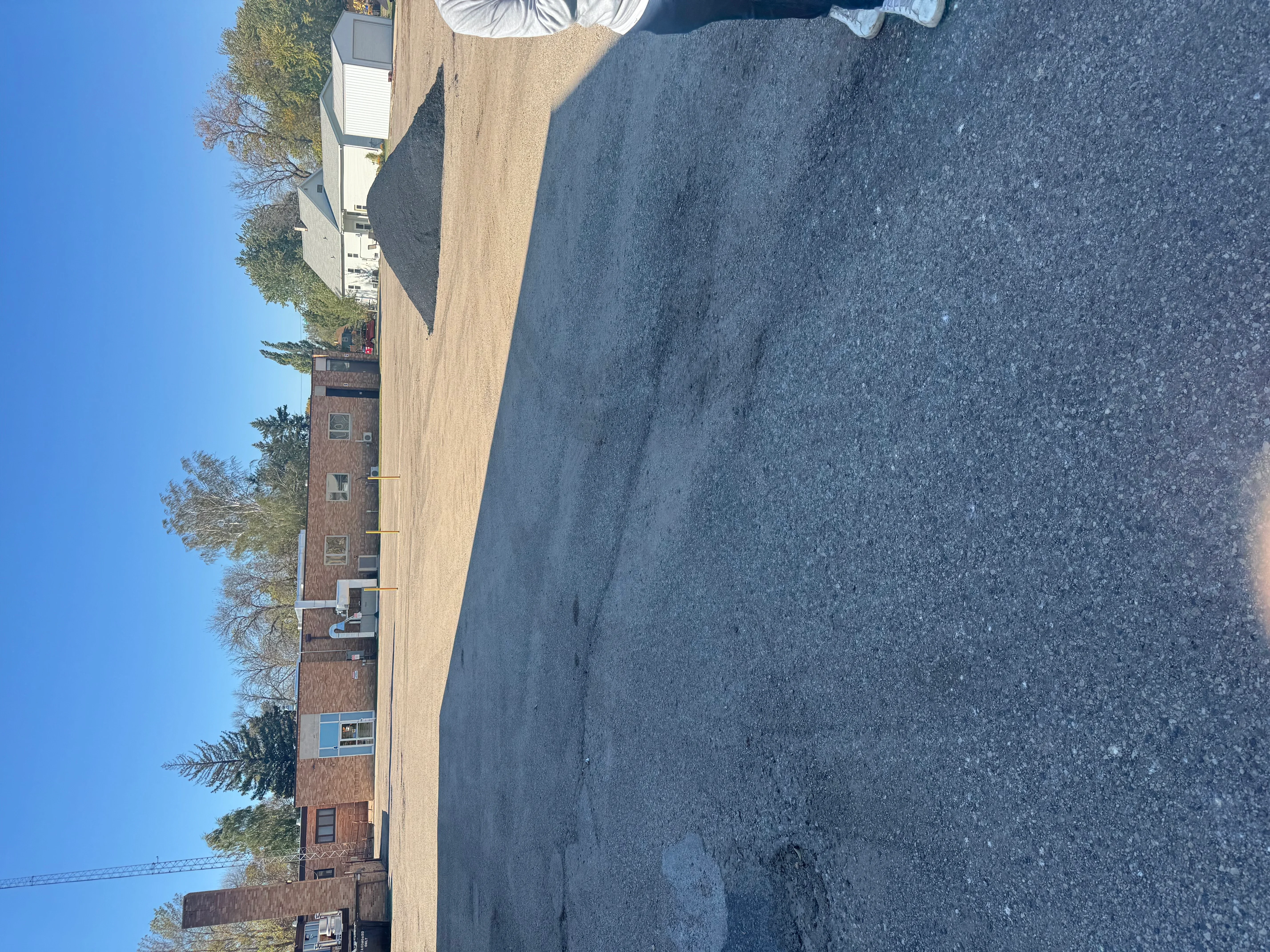 New asphalt driveway paving next to brick residential home with clear surface finish
