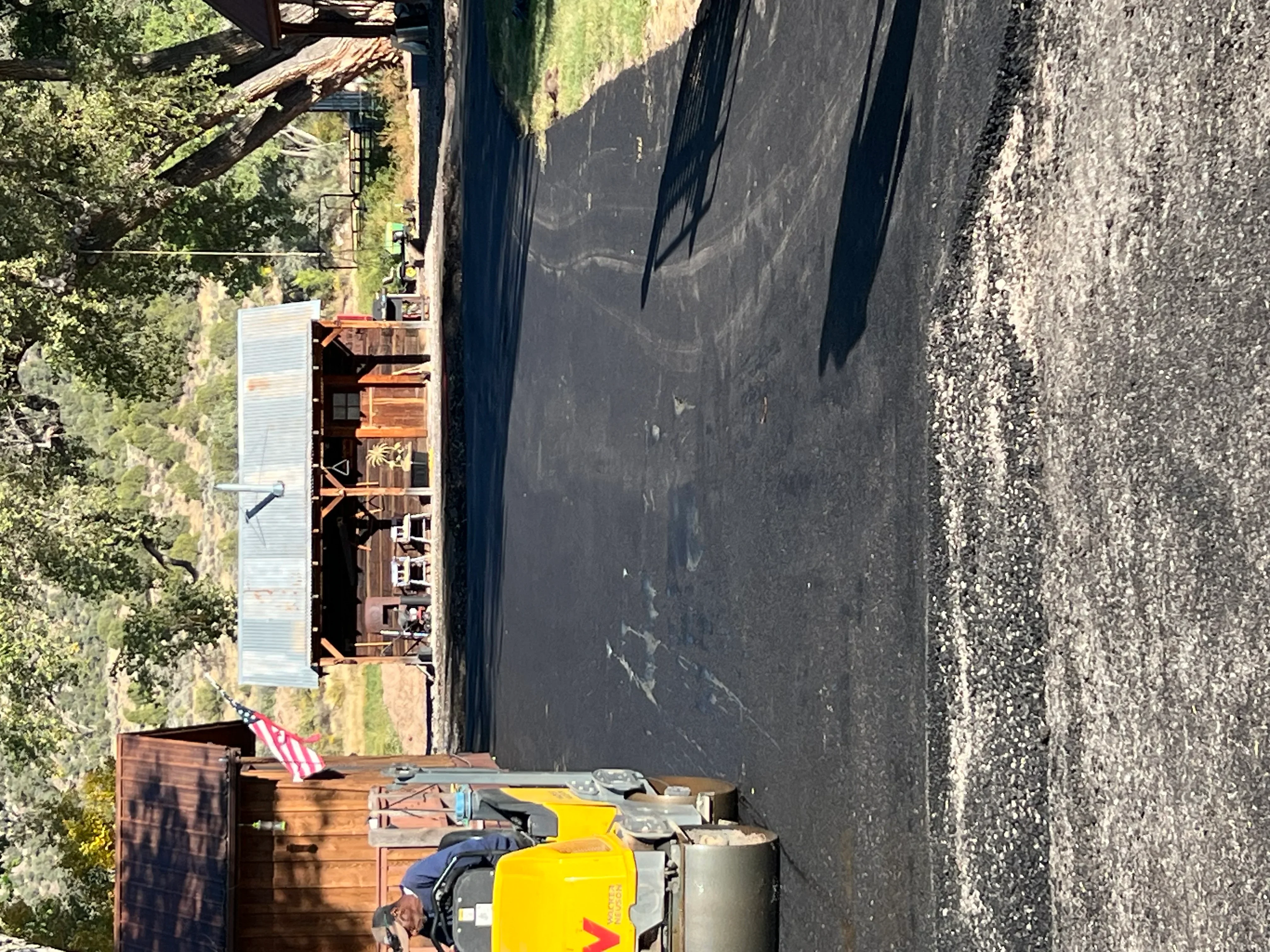 Newly paved asphalt driveway with dark surface next to concrete, residential setting
