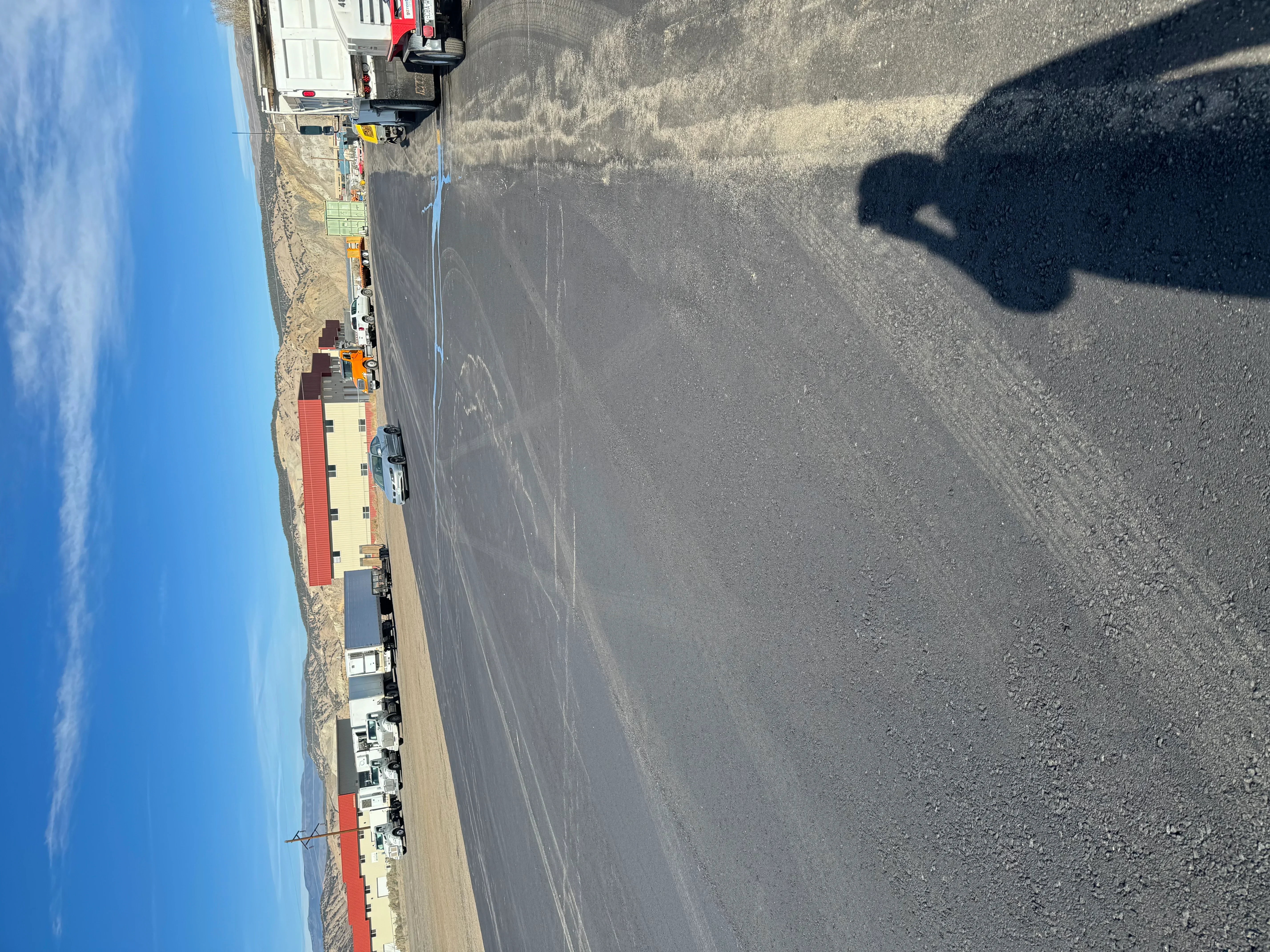 Newly paved asphalt driveway with dark surface and clean edges adjacent to residential property