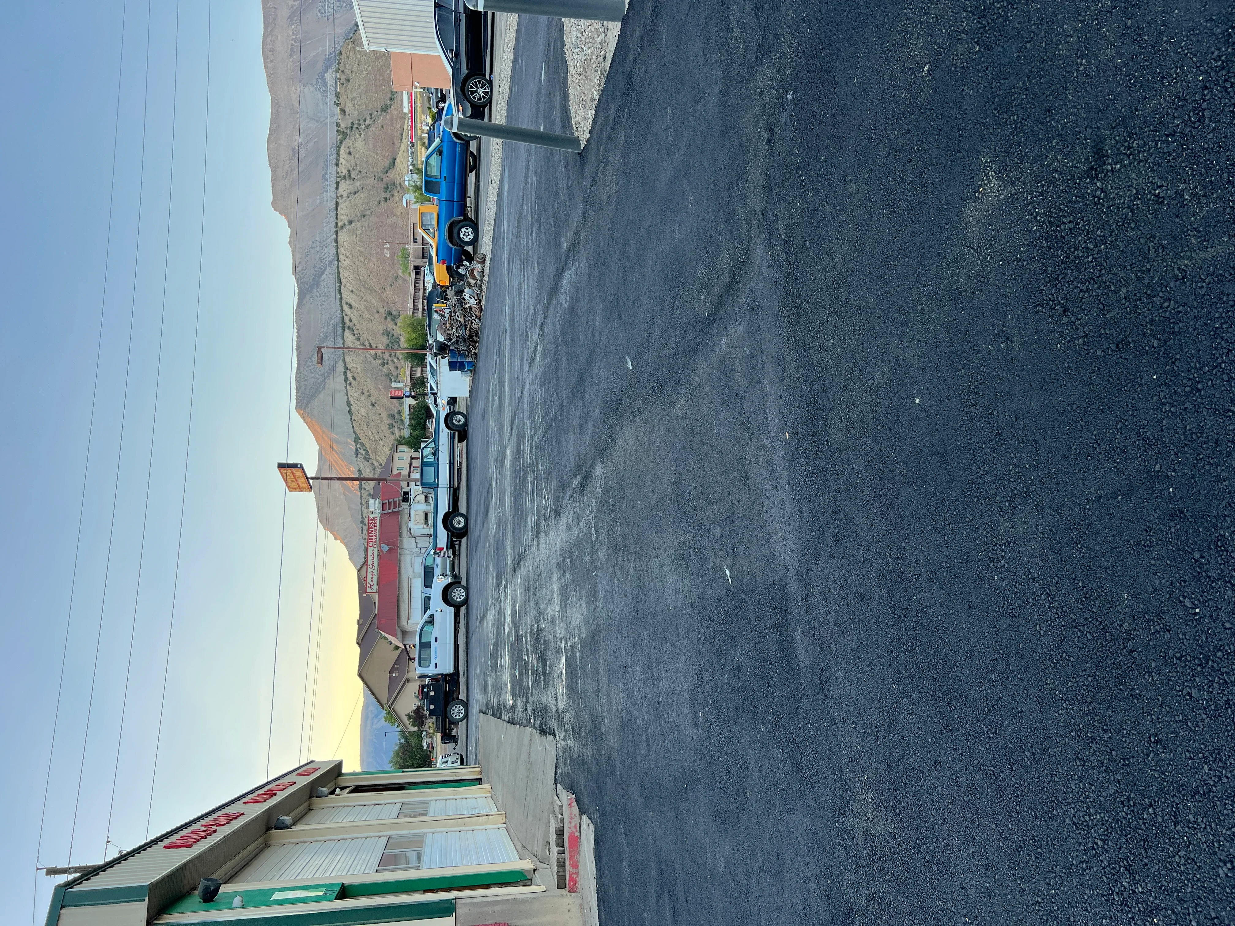 Commercial parking lot with newly installed dark asphalt paving and construction equipment