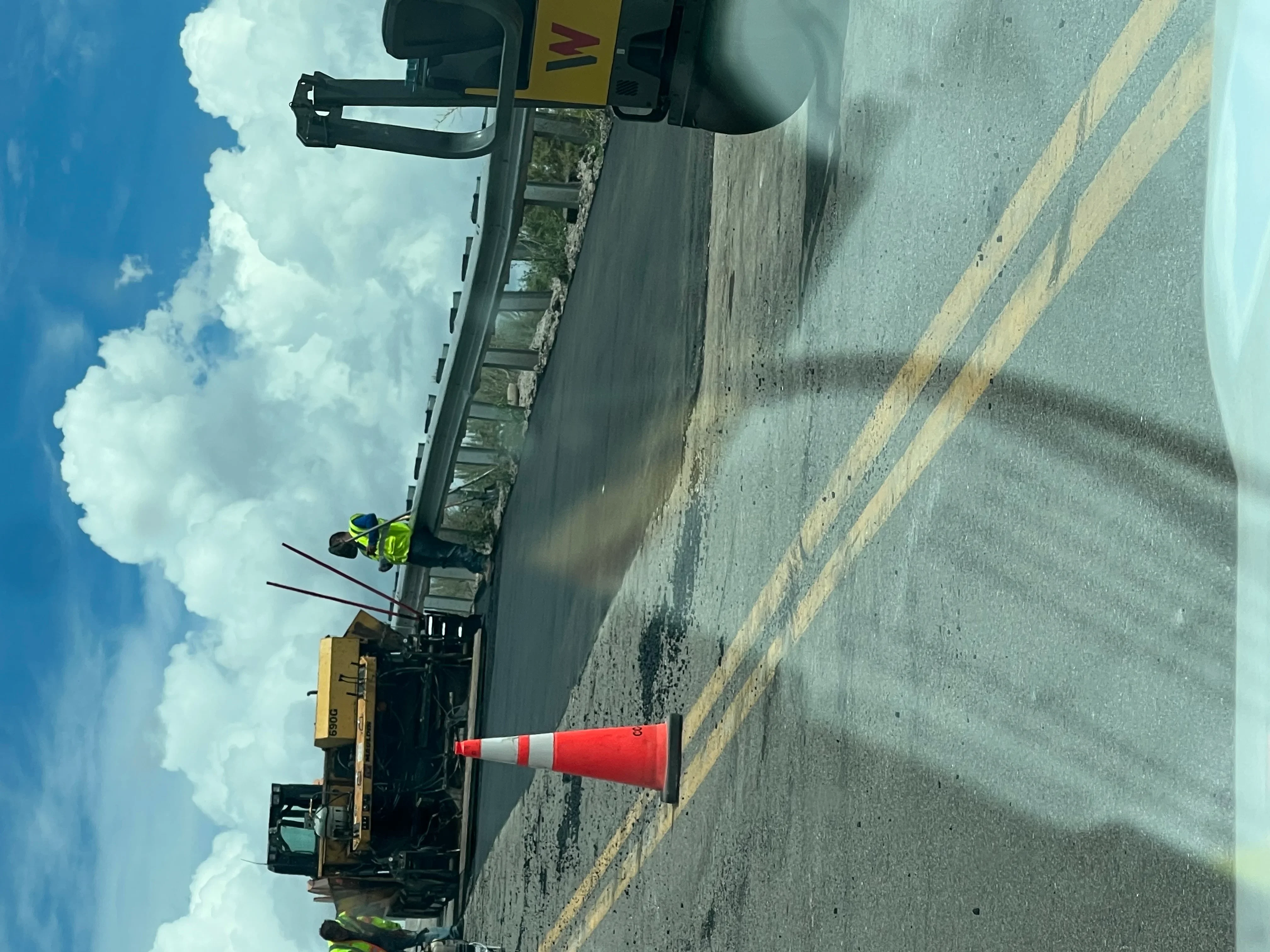 Asphalt road with yellow center line striping and traffic control equipment during marking operation
