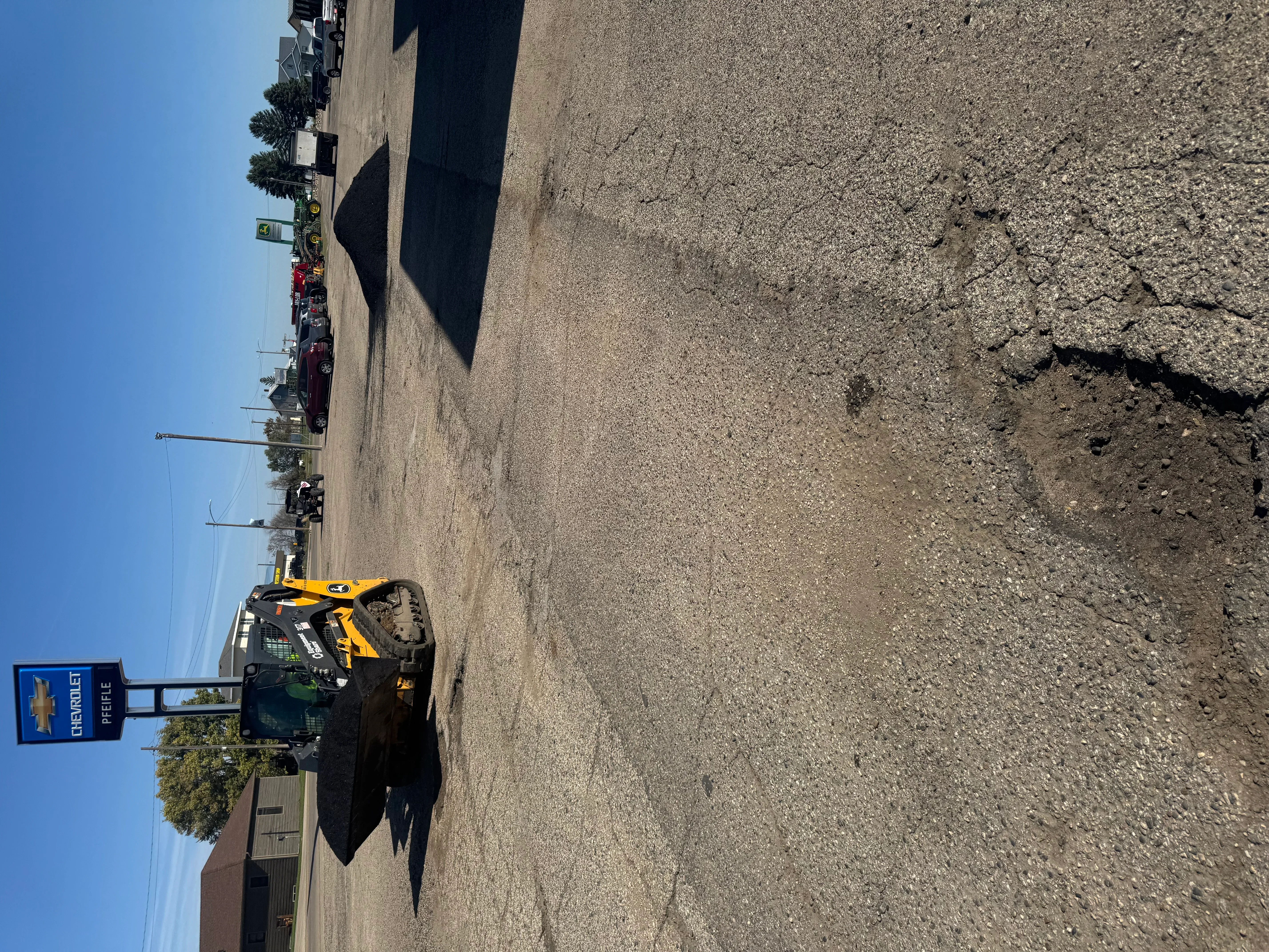 Asphalt paving equipment compacting fresh asphalt on large commercial parking lot