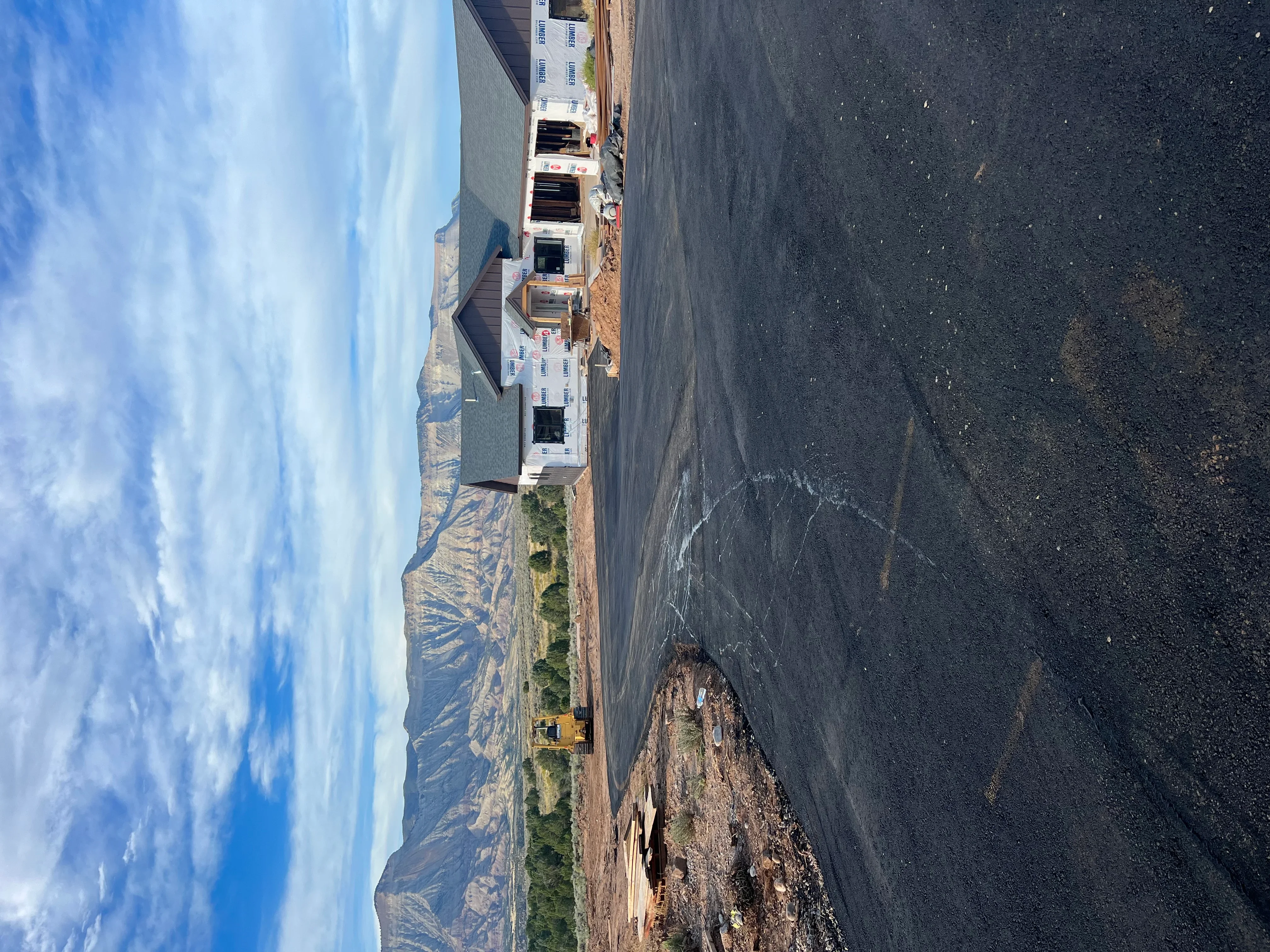 Fresh black asphalt driveway with protective paper covering on residential property