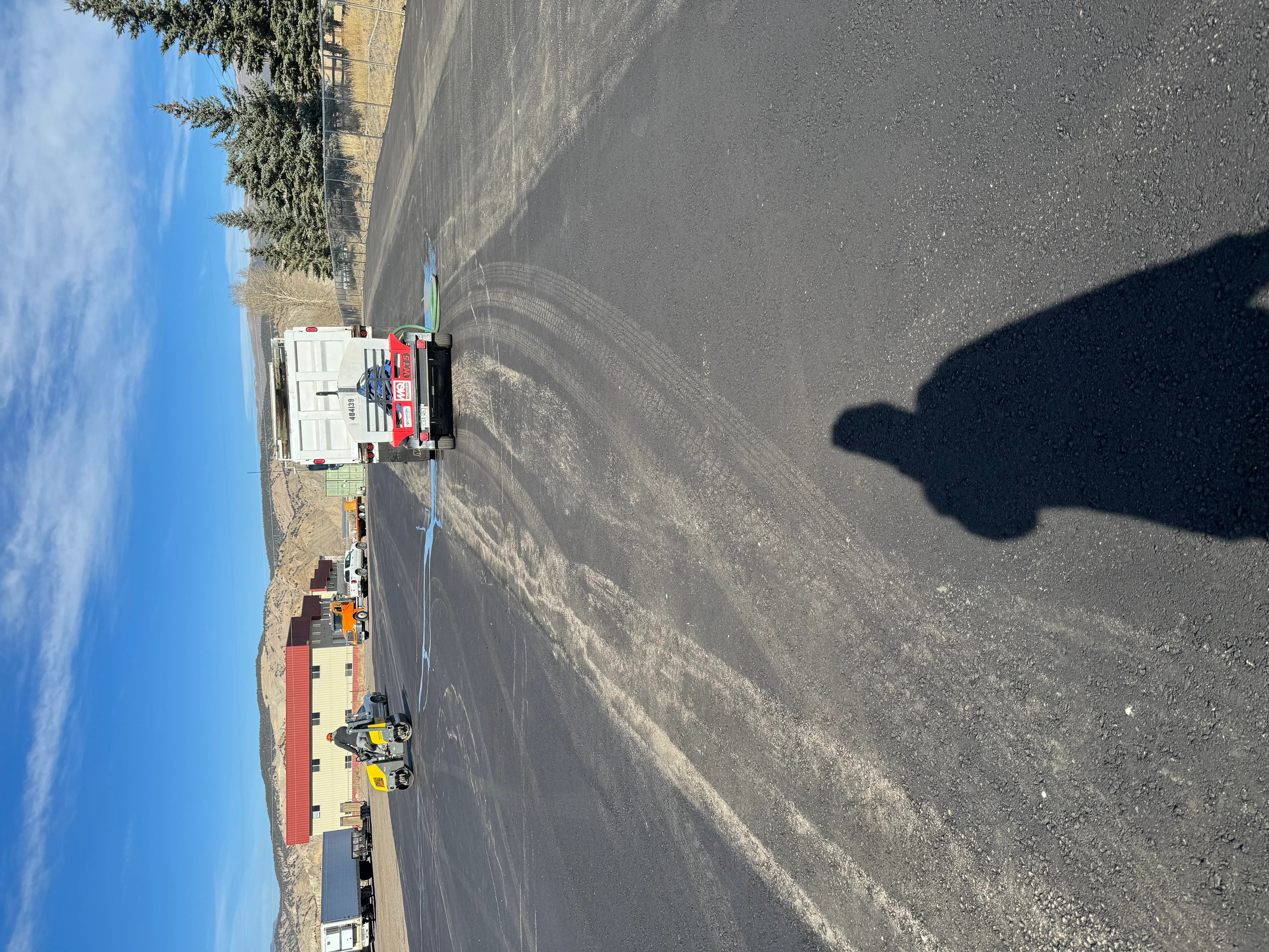 Newly paved asphalt driveway with compaction equipment and paving truck on site