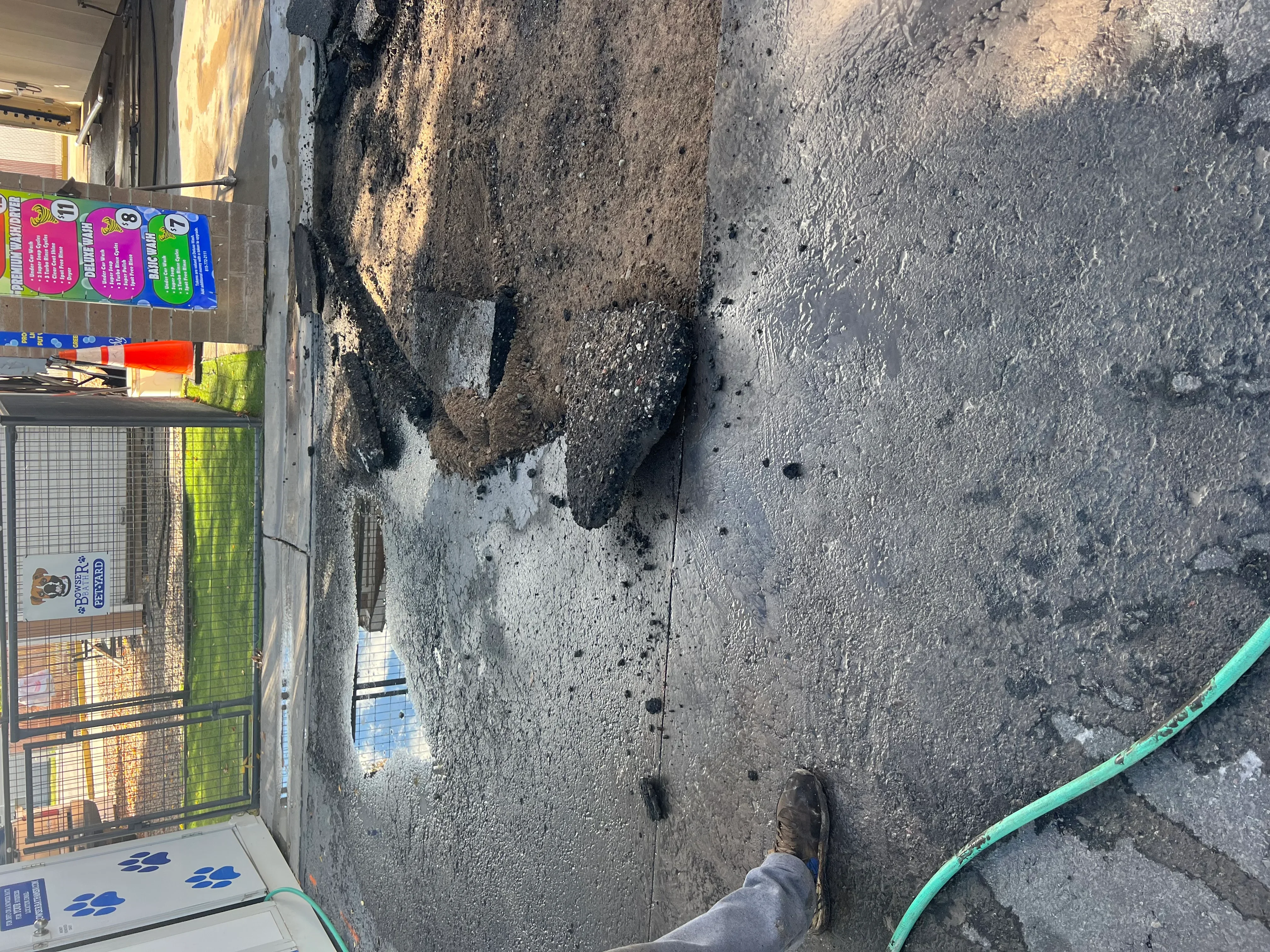 Repaired asphalt pothole with fresh patch material on worn pavement surface